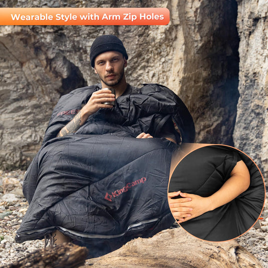 KingCamp FREESPACE 300 Wearable Sleeping Bag – Waterproof, Extra Wide Flannel Camping Sleeping Bag Person using a black wearable sleeping bag with arm zip holes in a natural setting.